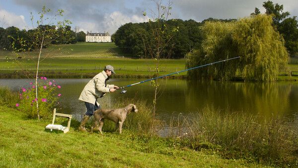 Homme qui pêche avec son chien sur l'étang du domaine, hôtel de charme Allier, Château d'Ygrande