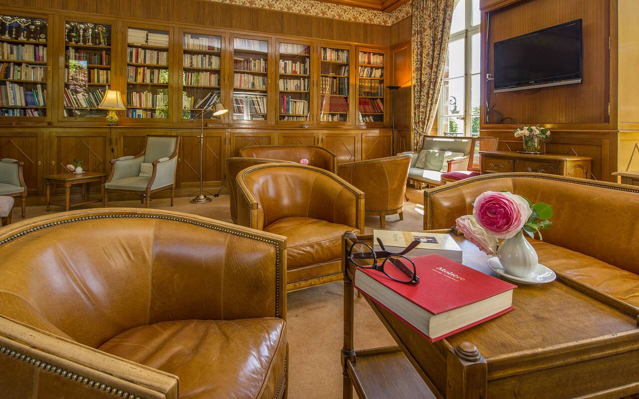 Salon-bibliothèque du Château d’Ygrande, près de Vichy, avec fauteuils en cuir et bibliothèques vitrées.