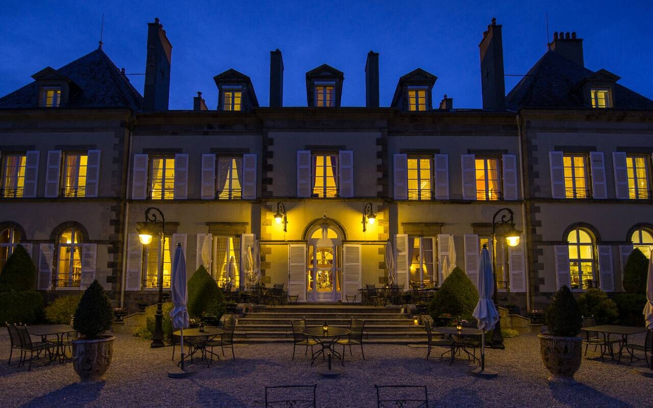 Façade éclairée du Château d’Ygrande en Auvergne à la nuit tombée.