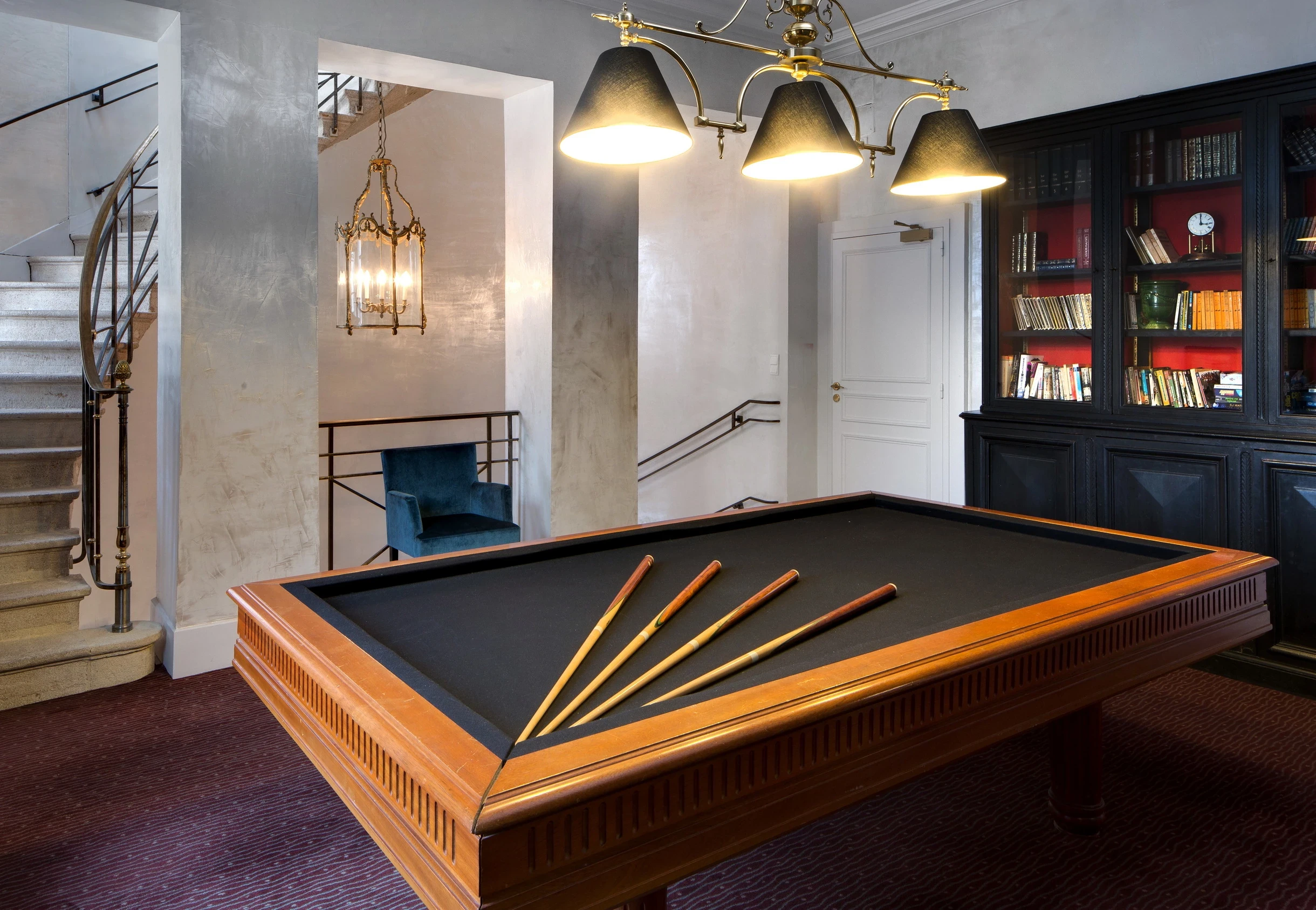 Table de billard devant une bibliothèque vitrée au Château d’Ygrande, en Auvergne.