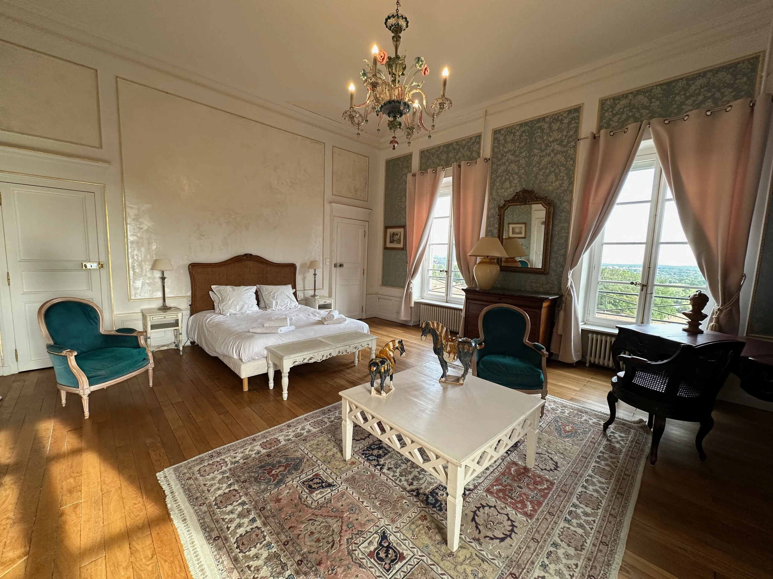 Lit à tête cannée et coin salon dans une chambre d’hôtes du Château d’Ygrande en Auvergne.