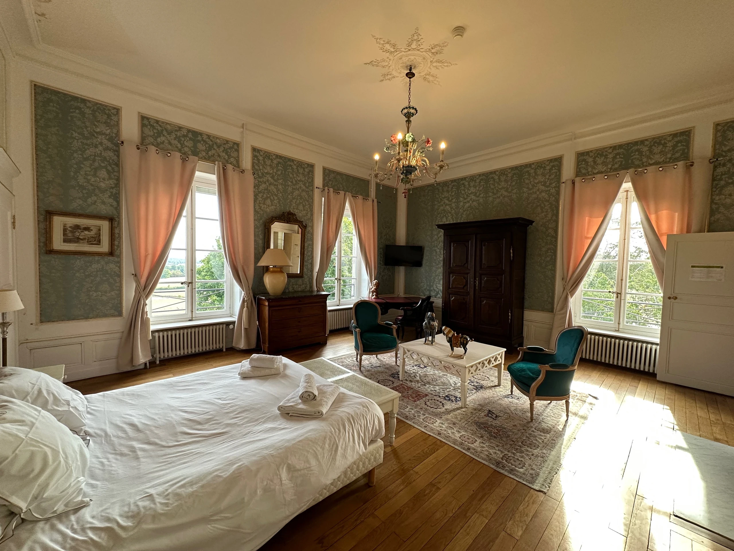 Coin salon avec fauteuils verts près des grandes fenêtres d’une chambre d’hôtes du Château d’Ygrande en Auvergne.