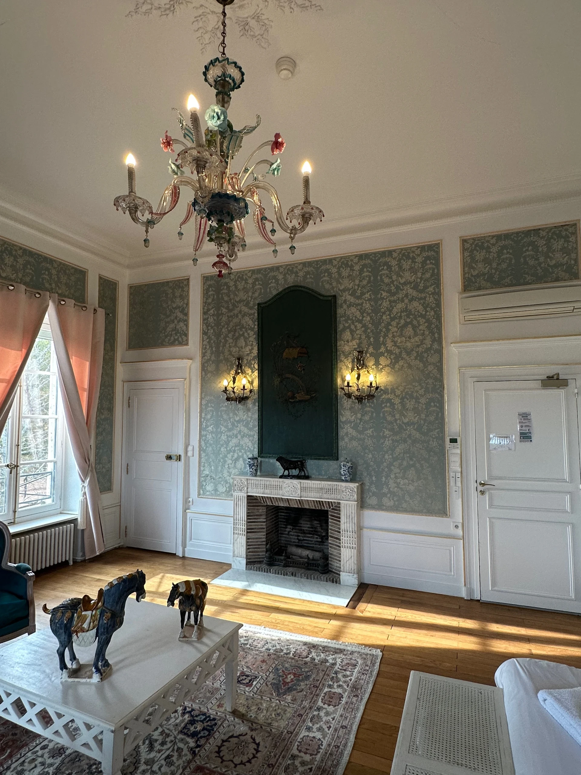 Lustre à fleurs en verre et cheminée sculptée dans une chambre d’hôtes en Auvergne, au Château d’Ygrande.