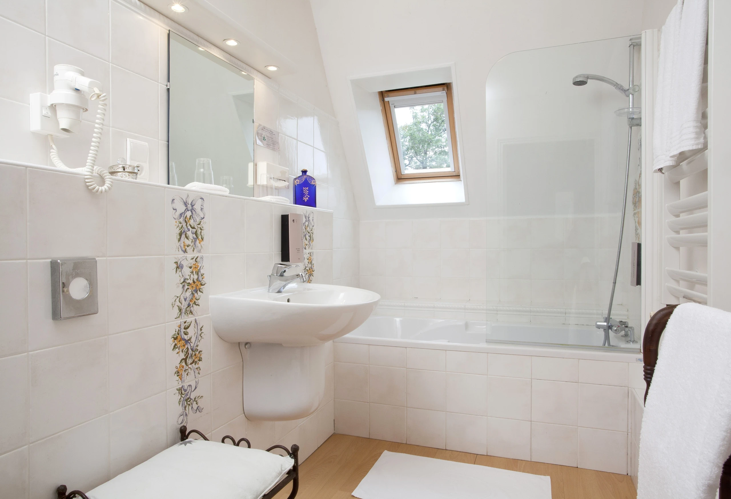 Baignoire avec pare-douche vitré dans la salle de bains d’une chambre d’hôtes du Château d’Ygrande en Auvergne.
