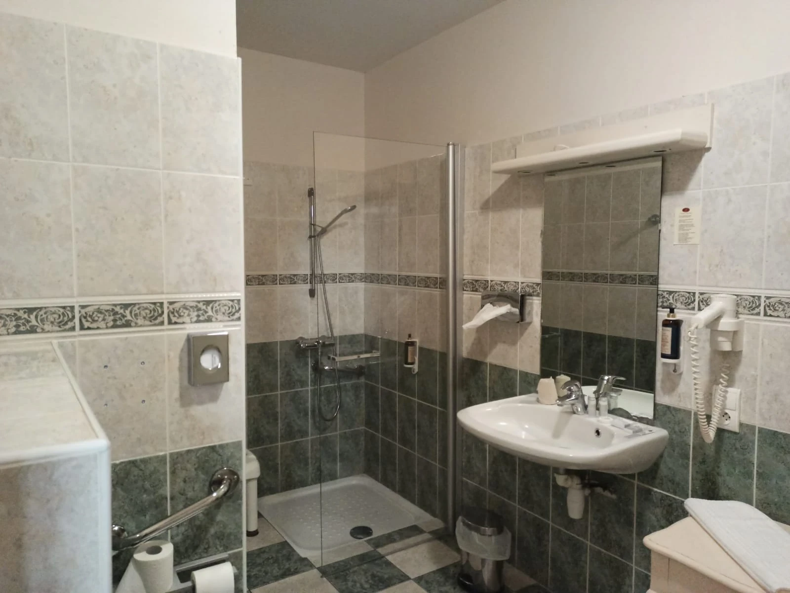 Salle d’eau d’une chambre d’hôtes en Auvergne, avec douche vitrée et lavabo sous un grand miroir.