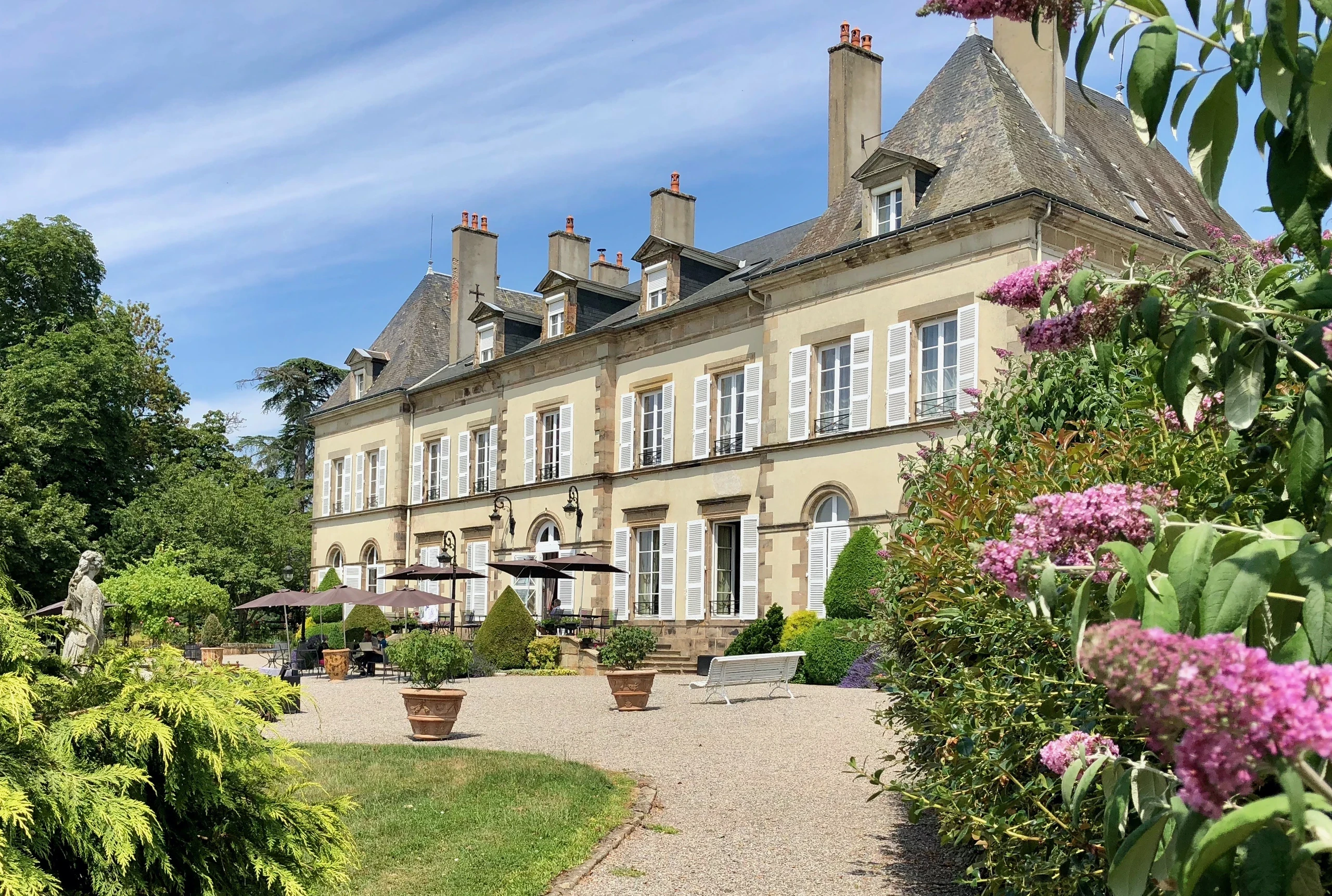 Façade et terrasse fleurie des chambres d’hôtes du Château d’Ygrande en Auvergne.