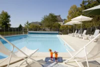 Piscine du Château d’Ygrande en Auvergne, avec deux cocktails entre des chaises longues au premier plan.