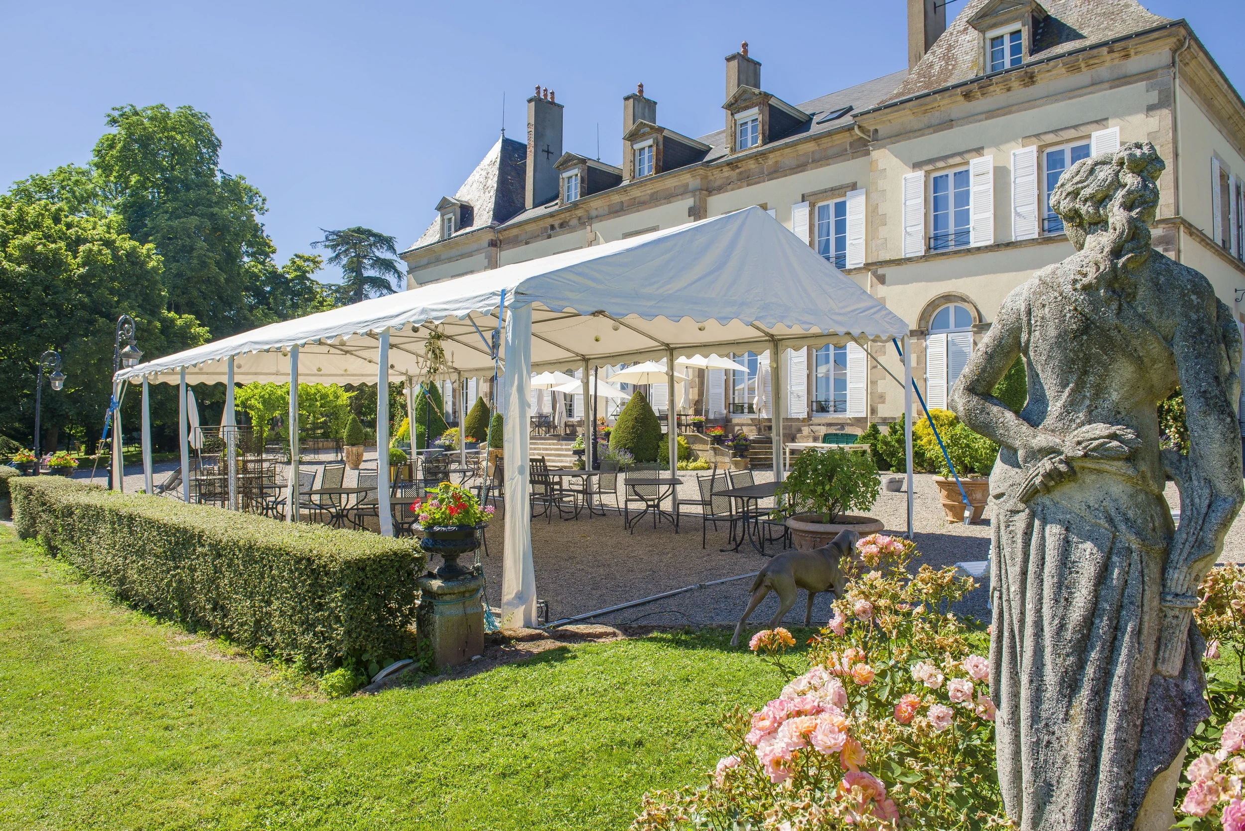 Tente de réception devant la façade du Château d’Ygrande, en Auvergne, avec des tables et des chaises dans le jardin.