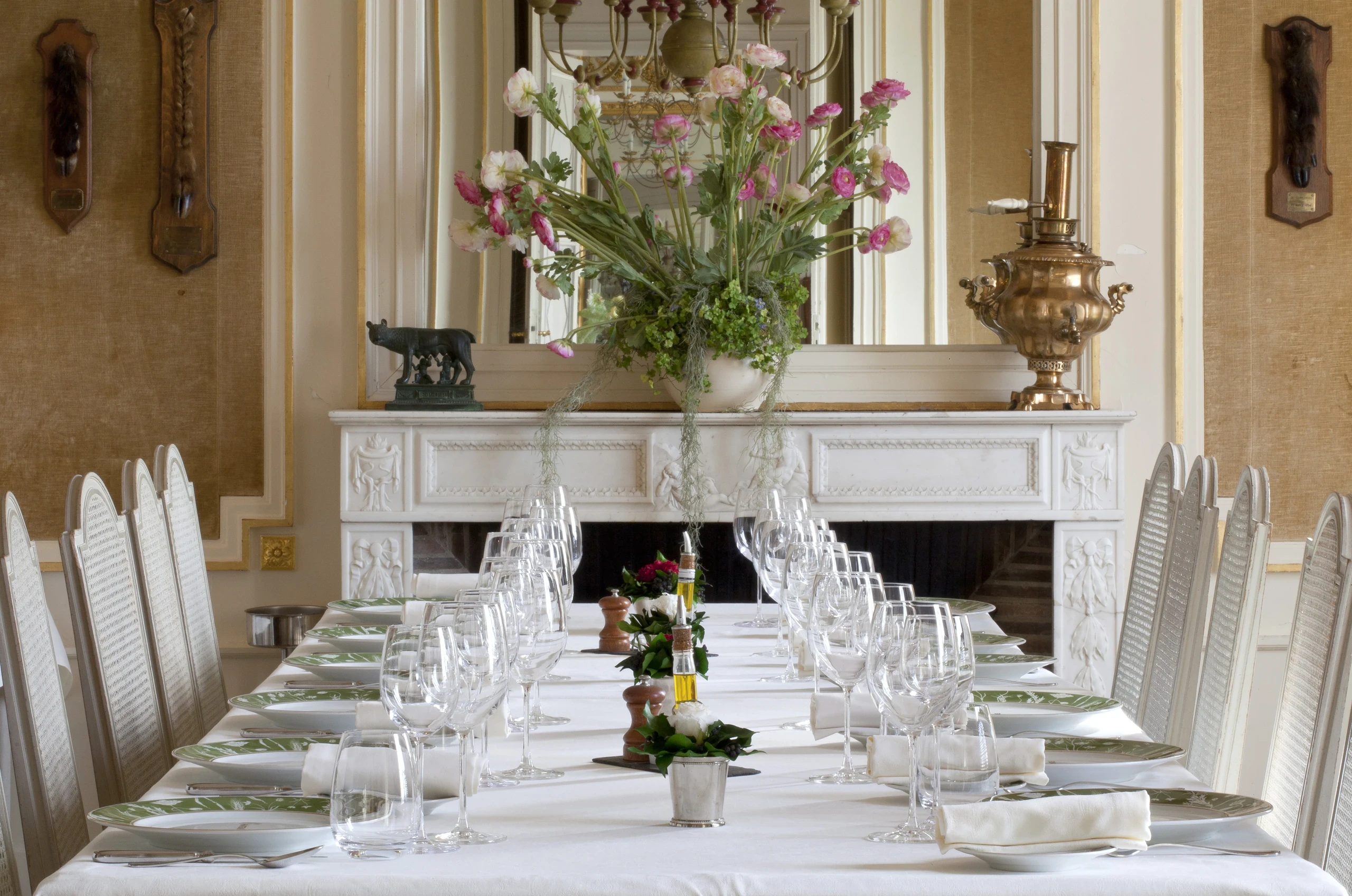 Table dressée face à une cheminée en marbre et à un grand bouquet au Château d’Ygrande, en Auvergne.